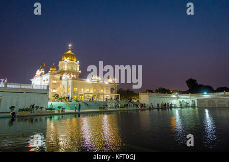 Delhi, Indien - 19. September 2017: unbekannte Menschen zu Fuß vor dem Hauptgebäude des Sikh Schreine von Delhi - Gurudwara Bangla Sahib. Das Hauptgebäude des Tempels beleuchtet ist und in sarowar Teich Wasser in Indien wider. Stockfoto