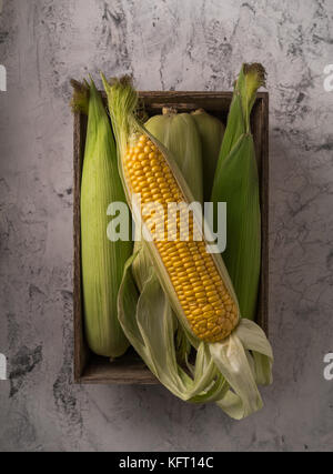 Kiste voller frische Maiskolben auf dem alten Beton Stockfoto