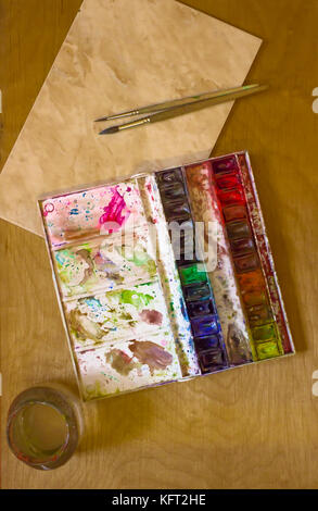 Professionelle schmutzig Aquarell Aquarell Farben in Box mit Pinsel, Palette und Wasserkrug auf Holzbrett Stockfoto