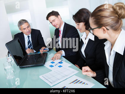 Gruppe von verschiedenen Geschäftsleute halten ein Meeting um einen Tisch herum diskutieren, Graphiken, die statistische Analyse Stockfoto