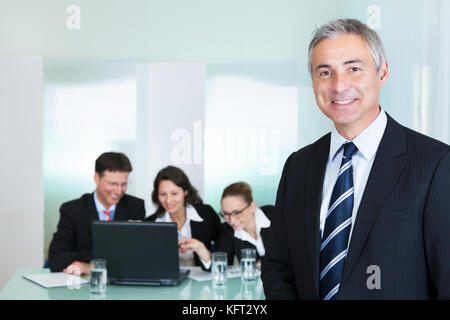 Corporate Promotion und Leadership Konzept mit einem erfolgreichen schönen Lächeln, Geschäftsmann, stehen im Vordergrund, während seine Kollegen Stockfoto