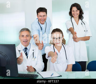 Happy medizinisches Team compridsing Männliche und weibliche Ärzte breit grinsend und mit einem Daumen nach oben von Erfolg und hoffe Stockfoto