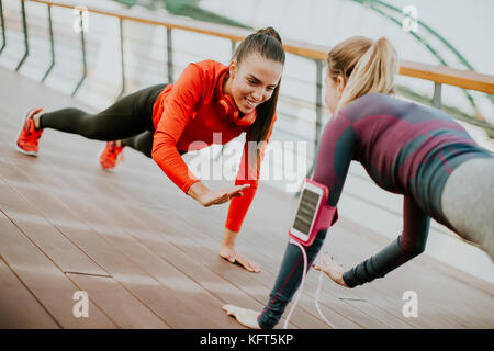 Zwei junge Frauen, die Plank am Riverside nach dem Ausführen Stockfoto