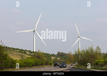 Zwei Windkraftanlagen Erzeugung erneuerbarer Energien oberhalb einer Straße in South Yorkshire, Großbritannien Stockfoto