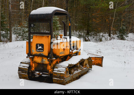Der rostige alte John Deere 450C-Planierraupe parkte auf einem Feld im Schnee in den Adirondack Mountains, NY, USA. Stockfoto
