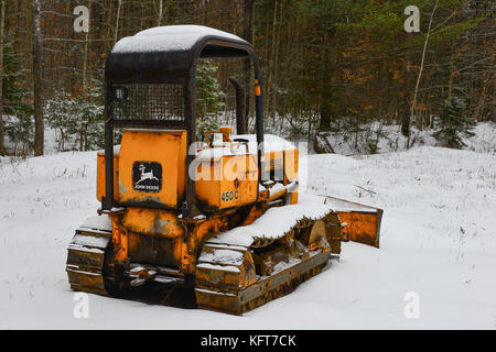 Rostige alte John Deere 450c Planierraupe in einem Feld im Schnee in den Adirondack Mountains, NY, USA geparkt. Stockfoto