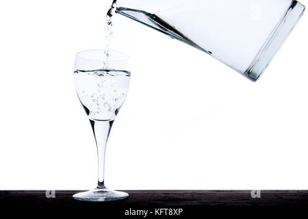 Füllung Glas mit Wasser aus einem Krug Stockfoto