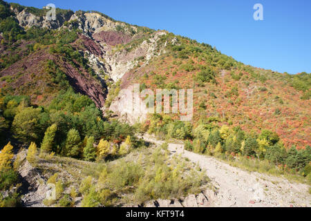 Herbstliche Farben und tief erodierte Berghänge im Tinée Valley. Saint-Sauveur-sur-Tinée, Hinterland der französischen Riviera, Alpes-Maritimes, Frankreich. Stockfoto