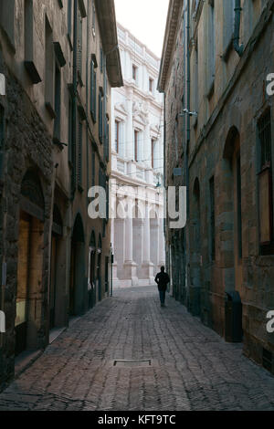 Silhouette eines Mannes, der auf einer verlassenen schmalen Straße läuft. Città Alta (Oberstadt), Bergamo, Provinz Bergamo, Lombardei, Italien. Stockfoto