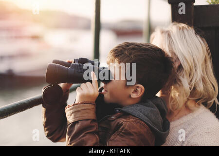 Glücklichen kleinen kaukasischen Jungen beobachten, den Blick, für die Suche, durch ein Fernglas mit Mutter Stockfoto