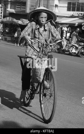 Ältere Radfahrerin in den Straßen von Hanoi, Vietnam Stockfoto