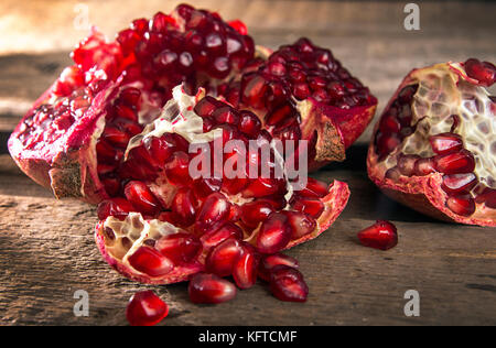 Gebrochene Granatapfel. Granatapfel Körner. Granatapfel schließen bis auf hölzernen Tisch Stockfoto