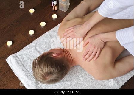 Frau tun Massage Mann. Ihre Hände auf seinem Rücken Stockfoto