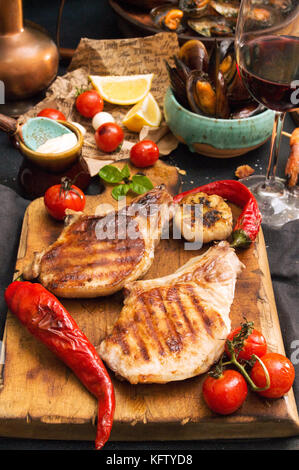 Overhead von Tisch. Sortierte Köstliches vom Grill Grill Fleisch und Fisch mit Gemüse. Schweinefleisch Steaks gegrillt, gegrillter Lachs Forelle, Muscheln, shr Stockfoto