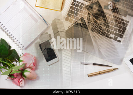Feminine Workspace - Arbeitsbereich mit Tastatur, Telefon und Blumen, Double Exposure mit modernen Stadtbild Stockfoto