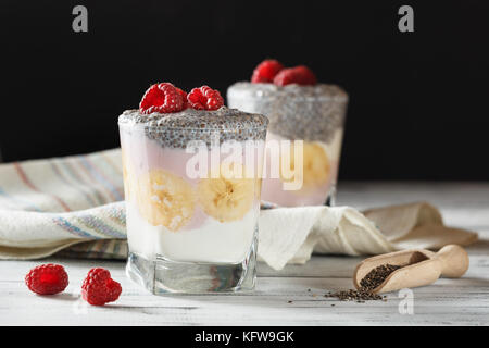 Joghurt mit Chia Samen und Früchte, Bananen und Himbeeren. gesundes Frühstück oder Snack am Morgen Konzept Stockfoto