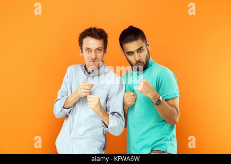 Zwei starke Boxer. aggressiv mans Ernst loocking an Kamera, bereit zu kämpfen. Studio erschossen. Auf orange Hintergrund isoliert Stockfoto