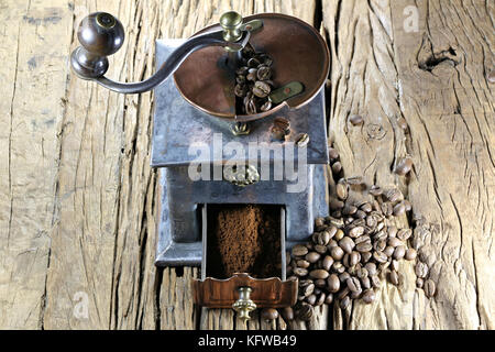 Vintage Kaffeemühle mit Herstellung gerösteter indonesischen Arabica Kaffeebohnen auf rustikalen hölzernen Hintergrund Stockfoto