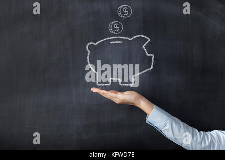 Tafel mit Hand und piggy Bank Stockfoto