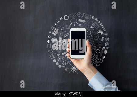 Hand mit einem Smart Phone, Geschäftskonzept Symbole auf Tafel Stockfoto