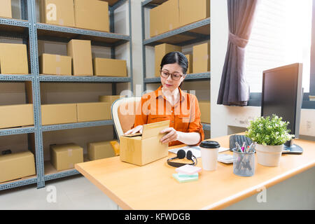 Professionelle junge weibliche Online shopping Eigentümer im Lager Büro Arbeitsplatz und Verpackung der Paketdienste Dialogfeld Vorbereiten für Kunden zu versenden Sitzen Stockfoto