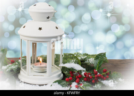 Magische Hintergrund mit weißen Laternen, Holly Zweige und Schnee auf rustikalem Holz. Weihnachten und Neujahr Thema. Stockfoto