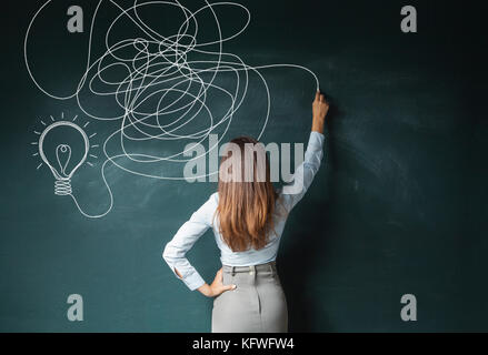 Business woman Zeichnung Glühbirne auf der Tafel Stockfoto