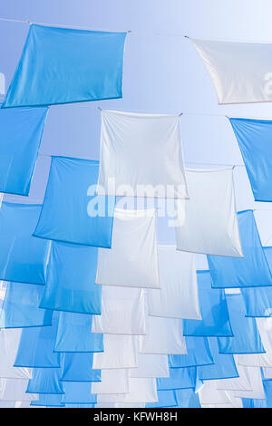 Große bunte, blau-weiße Girlanden, Banner, Dekoration, während der Feier vor einem blauen sonnigen Himmel. Stockfoto