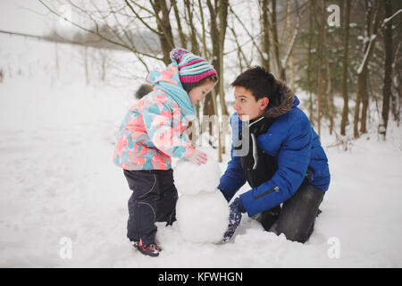 Mädchen macht Schneemann in Winter Park Stockfoto