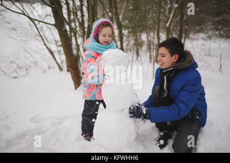 Mädchen macht Schneemann in Winter Park Stockfoto