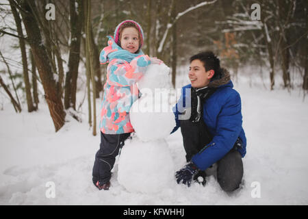 Mädchen macht Schneemann in Winter Park Stockfoto