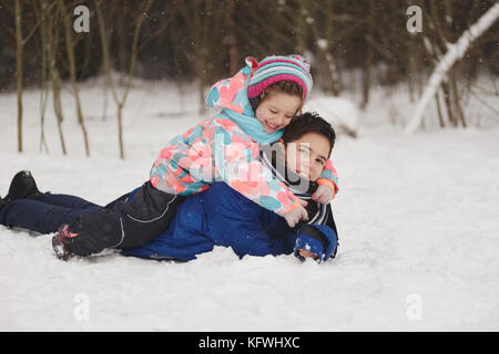 Mädchen und Jungen liegen auf dem Schnee Stockfoto