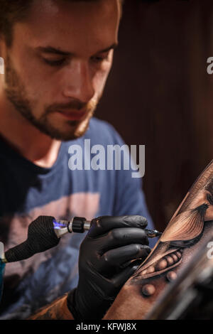 Professionelle Tätowierer macht ein Tattoo auf die Hand eines jungen Mannes Stockfoto