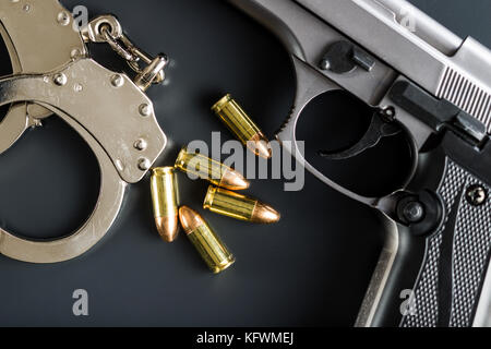 Pistole Munition, Pistole und Handschellen auf Schwarz. Stockfoto