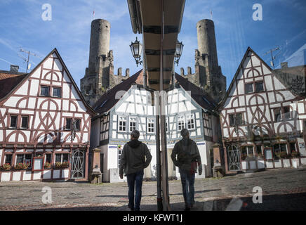 Eppstein, Deutschland. November 2017. Ein Passant spaziert durch die historische Innenstadt und genießt den Sonnenschein in Eppstein, Deutschland, 1. November 2017. Neben der Person befindet sich eine Glasscheibe, die die Ruine einer Burg reflektiert. Frank Rumpenhorst/dpa/Alamy Live News Stockfoto