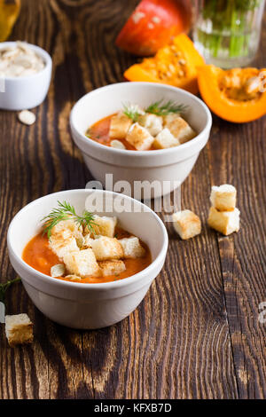 Butternut Kürbis-Suppe mit geröstetem Brot Topping, köstliche traditionelle Herbst Kürbis Teller auf rustikalen Holztisch Stockfoto