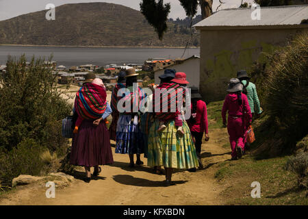 Farben von Bolivien, einer Gruppe von cholita Mütter und ihre Töchter und Babys zu Fuß durch die Pfade der Isla del Sol, Bolivien, Südamerika Stockfoto