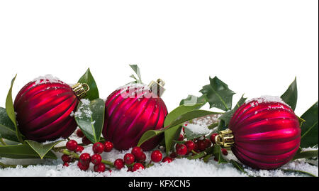 Weihnachten und Winter Hintergrund des neues Jahr. rote Kugeln und Stechpalme Beeren im schnee winter Thema. Stockfoto