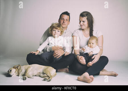 Zwei Generationen der Familie Studio Portrait mit Hund auf grauem und weißem Hintergrund. Stockfoto