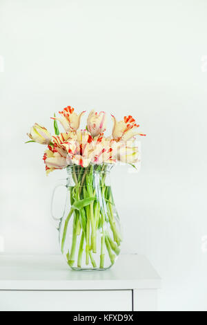 Schöne Tulpen Bündel in Glas Vase auf weißen Tisch an der weißen Wand. home interior Konzept. Frühling Stockfoto