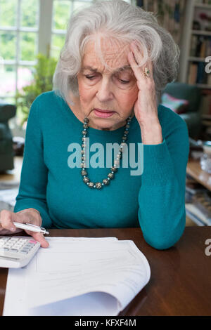 Ältere Frau, die durch Rechnungen und suchen besorgt Stockfoto