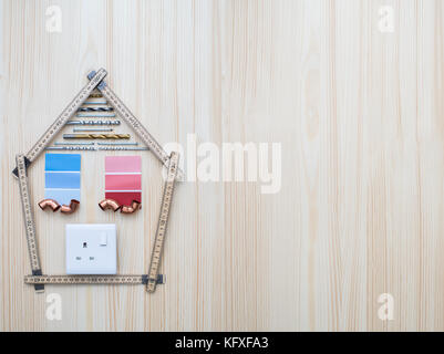 Bauteile in Form von Haus auf Holz- Hintergrund angeordnet Stockfoto