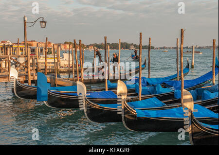 Gondeln liegen in der Riva degli Schiavoni in San Marco, Venedig, Italien. Die venezianische Lagune und die Insel San Giorgio Maggiore im Hintergrund. Stockfoto