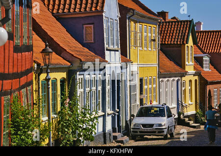 Aeroskobing, Dänemark - 4. Juli 2012 - schmale Kopfsteinpflasterstraße auf der Insel Aero mit bunten historischen Wohngebäuden, geparktem Auto, Pede Stockfoto