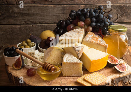 Die Zusammensetzung von Lebensmitteln mit Bausteinen von verschimmelten Käse, eingelegte Rosinen, Honig, Wein, Oliven, Feigen, Birnen, Cracker, Feigen auf alten hölzernen Hintergrund. Stockfoto