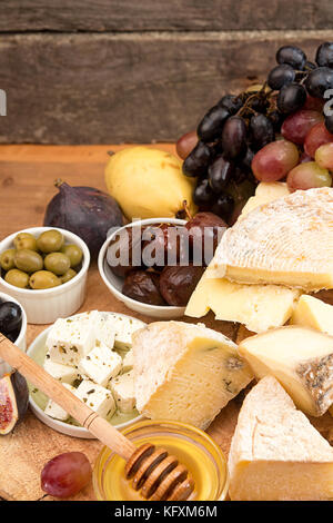 Die Zusammensetzung von Lebensmitteln mit Bausteinen von verschimmelten Käse, eingelegte Rosinen, Honig, Wein, Oliven, Feigen, Birnen, Cracker, Feigen auf alten hölzernen Hintergrund. Stockfoto