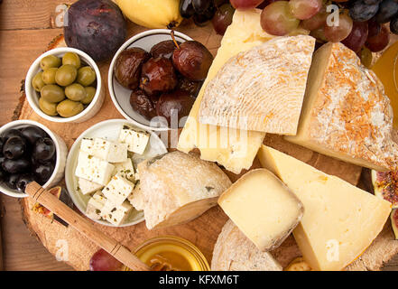 Die Gemeinkosten der Zusammensetzung von Lebensmitteln, die mit Bausteinen von verschimmelten Käse, eingelegte Rosinen, Honig, Wein, Oliven, Feigen, Birnen, Cracker auf alten Holz- Hintergrund. Zu Stockfoto