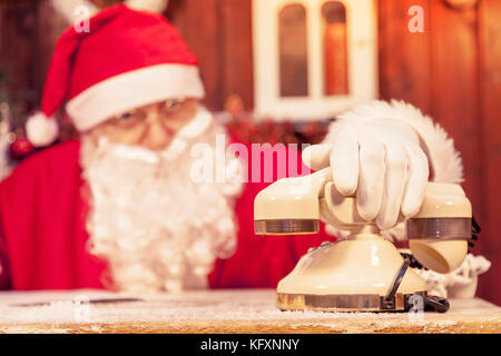 Portrait von Santa Claus erhält einen Anruf an seinem Haus stellt die Wunschzettel für Weihnachten Stockfoto