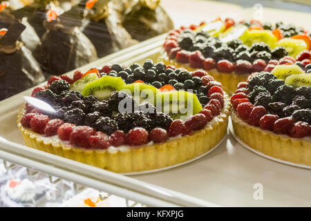 Frische süße Kuchen mit Johannisbeeren und Erdbeeren Beeren im Pastry Shop-Glas-Display an der Spitze Stockfoto