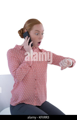 Schockiert Frau suchen bei smartwatch während Gespräch am Handy Stockfoto